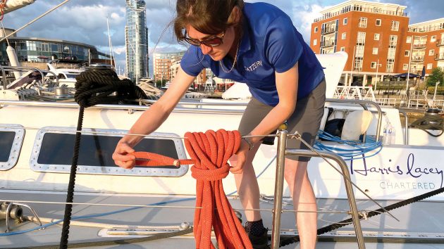 A lady neatly arranging rope on deck.
